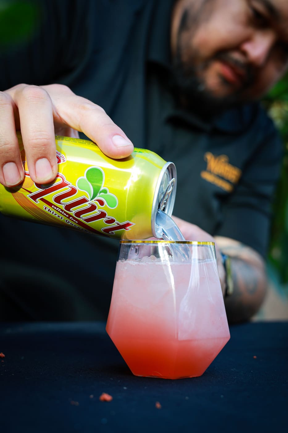 Wanderhive bartender topping a pink cocktail with grapefruit soda