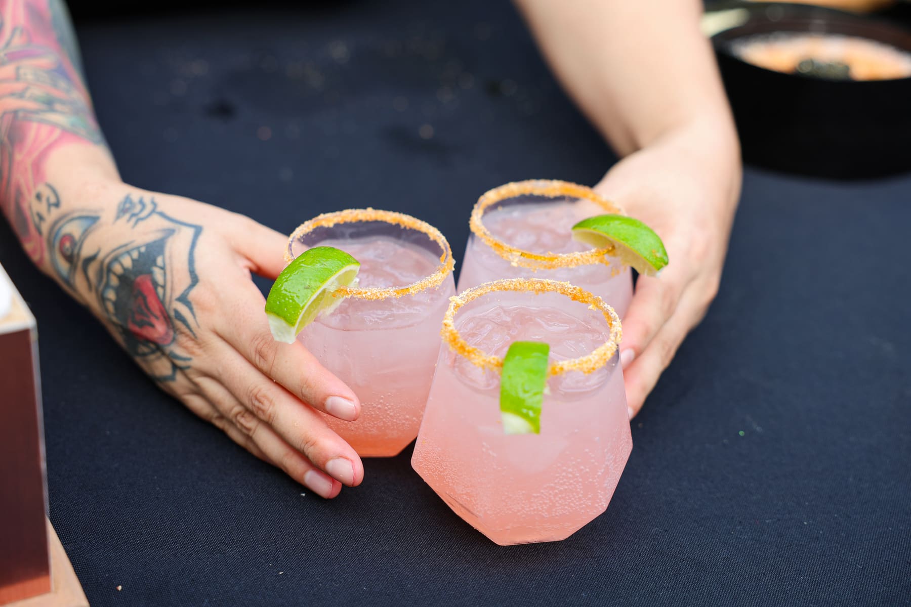 Three pink cocktails with spiced rims and lime wedges