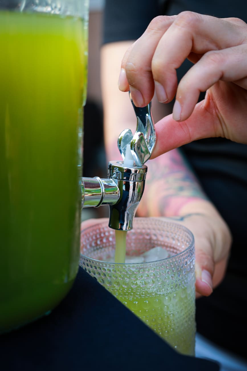 A fresh green drink poured from a glass dispenser